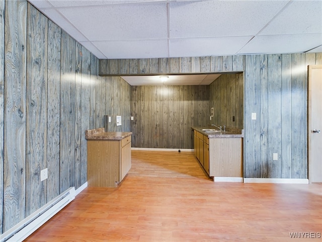 bar featuring a drop ceiling, a baseboard heating unit, sink, and light wood-type flooring