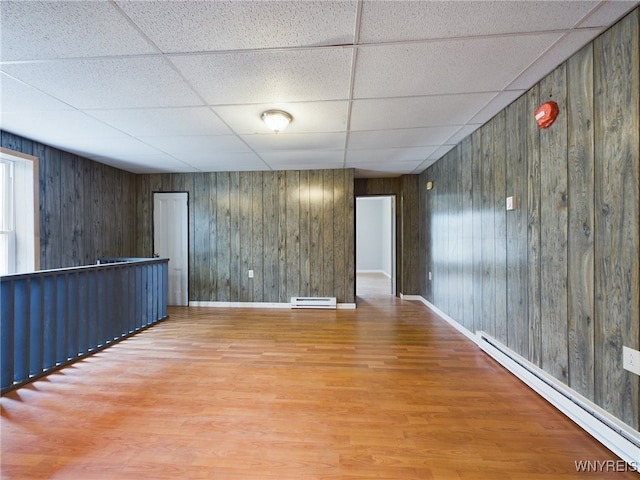 spare room featuring baseboard heating, a paneled ceiling, and hardwood / wood-style floors