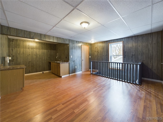 basement with a drop ceiling, sink, and wood-type flooring