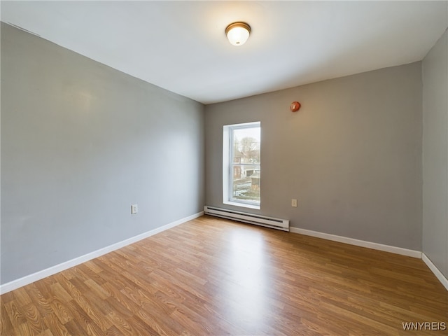 spare room with a baseboard heating unit and light wood-type flooring