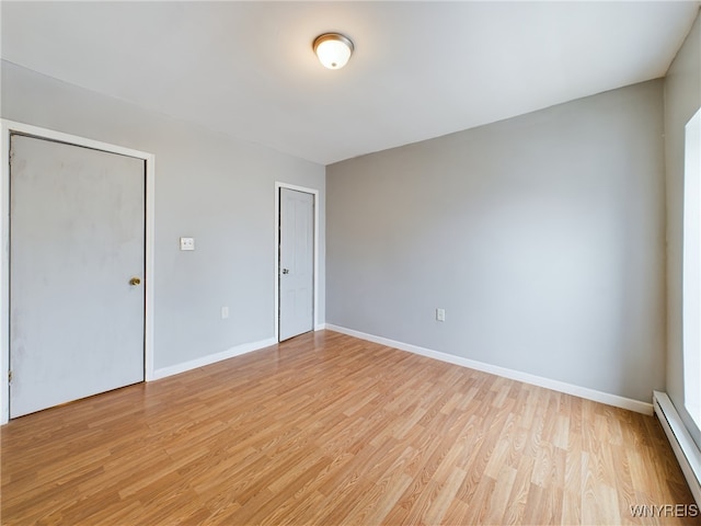 empty room featuring a baseboard radiator and light wood-type flooring