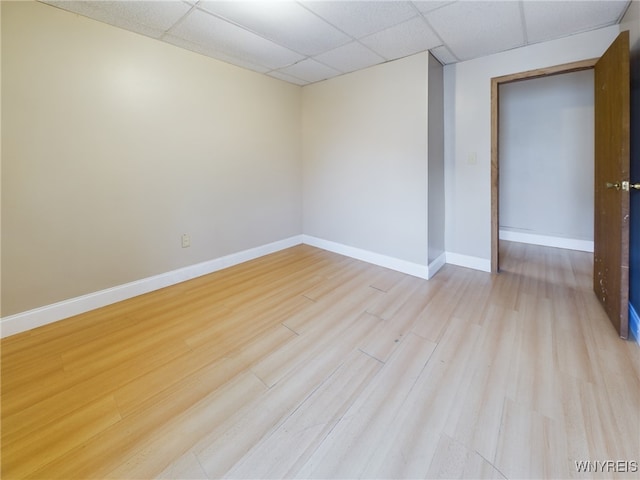 unfurnished room with a drop ceiling and light wood-type flooring