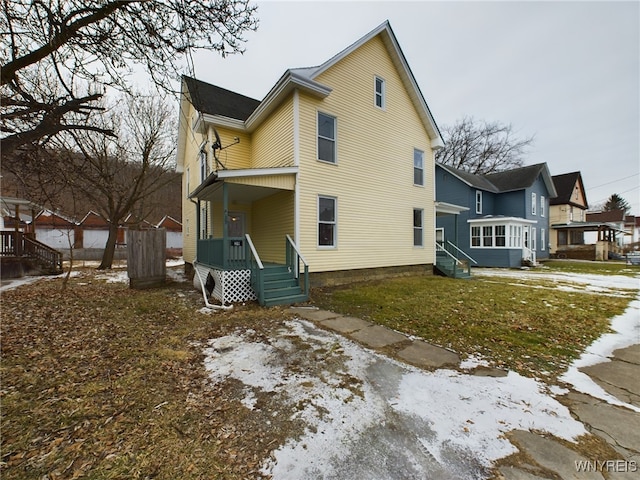 snow covered house featuring a yard