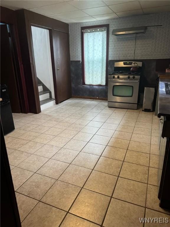 kitchen featuring stainless steel gas range, a drop ceiling, and light tile patterned floors