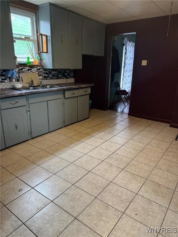 kitchen featuring dark countertops, light tile patterned floors, tasteful backsplash, and gray cabinets