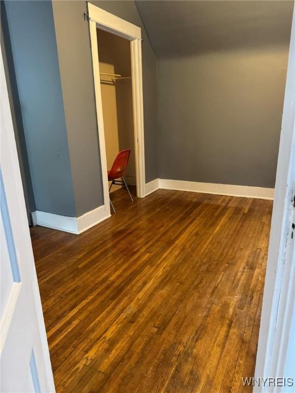 unfurnished bedroom with a closet, baseboards, and hardwood / wood-style flooring