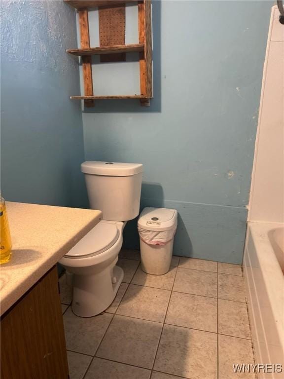 bathroom featuring toilet, tile patterned flooring, and a tub to relax in