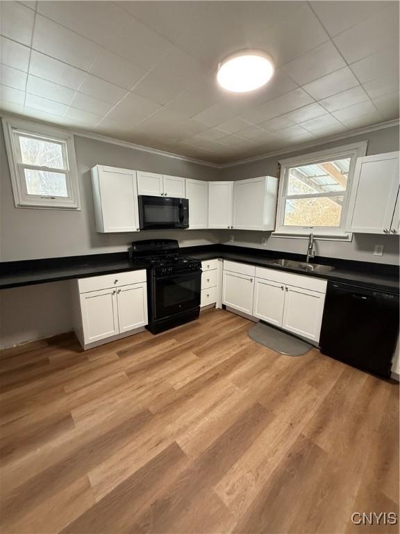 kitchen with sink, crown molding, black appliances, light hardwood / wood-style floors, and white cabinets