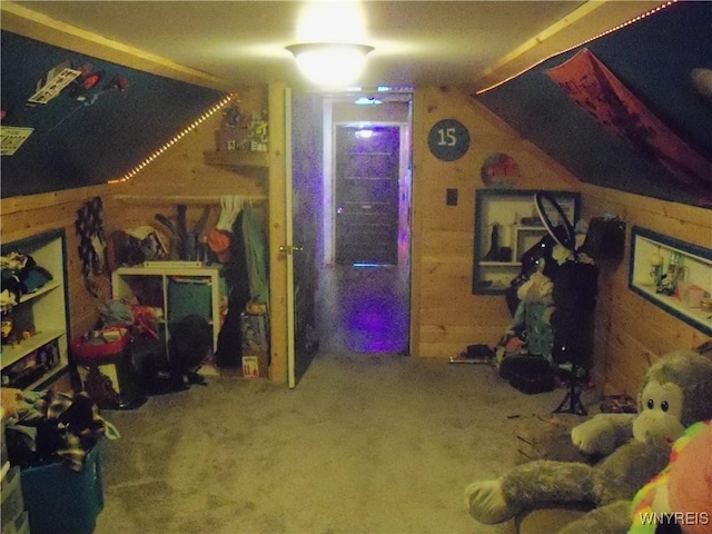 interior space featuring vaulted ceiling, carpet floors, and wood walls