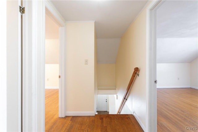 hall featuring crown molding, hardwood / wood-style flooring, and vaulted ceiling