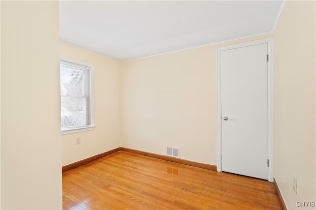 empty room with ornamental molding and light hardwood / wood-style floors