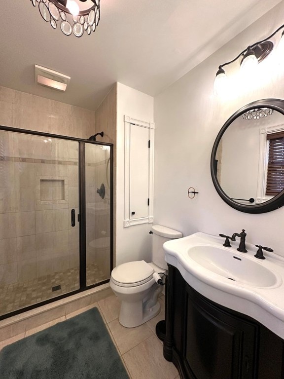 bathroom with tile patterned floors, vanity, toilet, and a shower with shower door