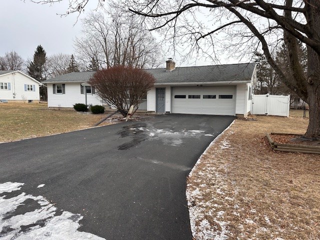 ranch-style house with a garage and a front lawn