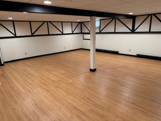 basement featuring a paneled ceiling and light hardwood / wood-style floors