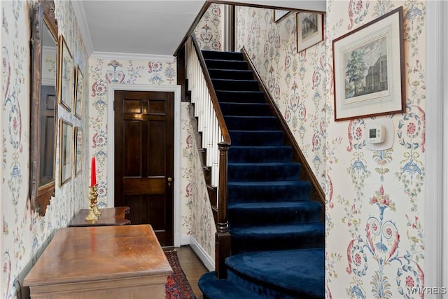 stairway with crown molding and wood-type flooring