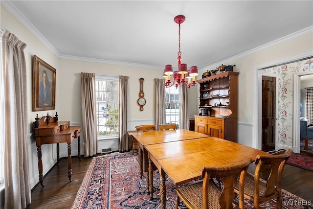 dining area featuring dark hardwood / wood-style flooring, ornamental molding, and an inviting chandelier