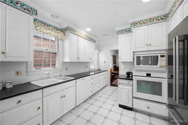 kitchen with white cabinetry, sink, and white appliances