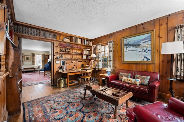 living room with hardwood / wood-style floors, a textured ceiling, and wood walls