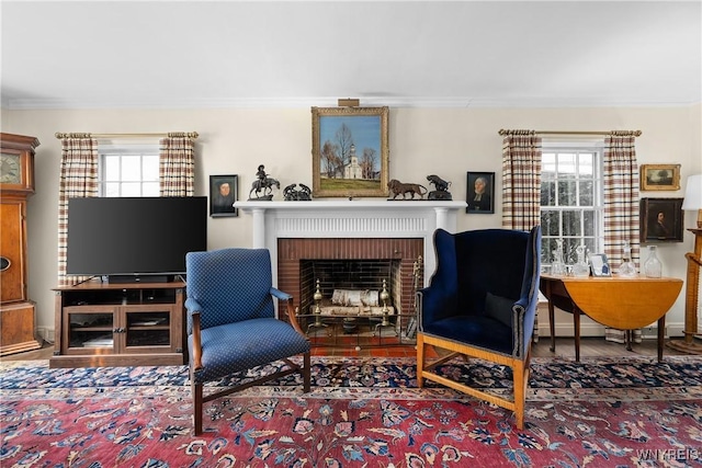 sitting room with ornamental molding, wood-type flooring, and a fireplace