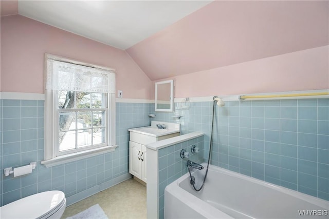 bathroom featuring vanity, toilet, vaulted ceiling, and tile walls