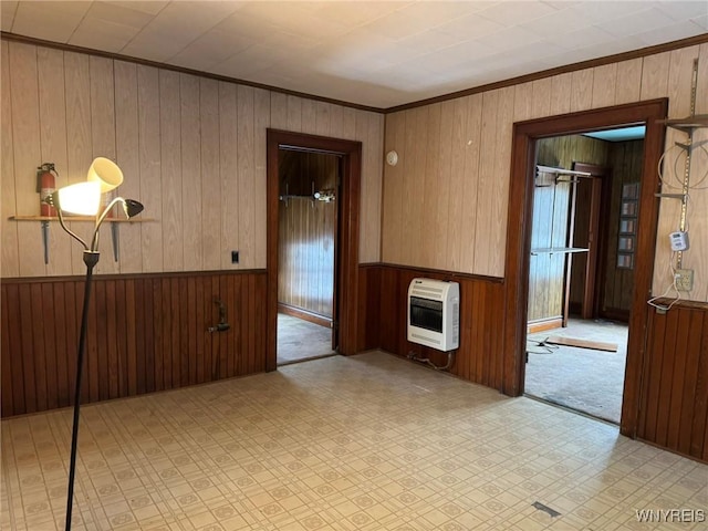 spare room featuring heating unit, wooden walls, and ornamental molding