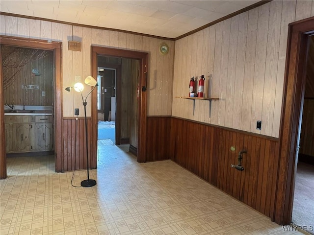 corridor with crown molding, wooden walls, and sink