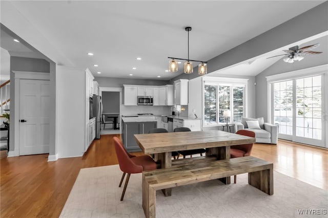 dining area with vaulted ceiling, sink, ceiling fan, and light hardwood / wood-style flooring