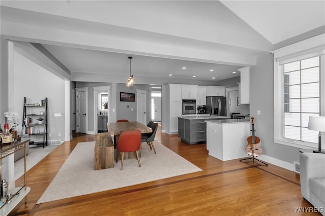 dining area with lofted ceiling and light wood-type flooring