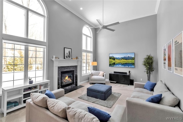 living room with crown molding, a fireplace, ceiling fan, and a towering ceiling