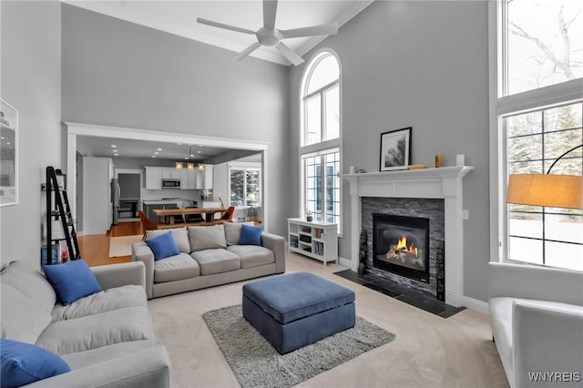 living room featuring a wealth of natural light, a towering ceiling, and light carpet