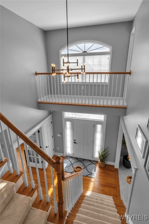 entryway featuring a towering ceiling, a notable chandelier, and light wood-type flooring