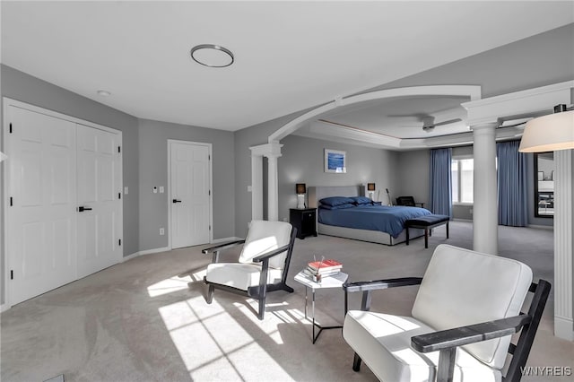 carpeted bedroom featuring a raised ceiling and decorative columns