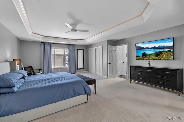 bedroom featuring ornamental molding, light colored carpet, ceiling fan, a raised ceiling, and a closet