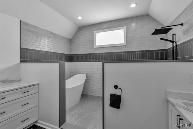 bathroom with lofted ceiling, independent shower and bath, vanity, and tile walls