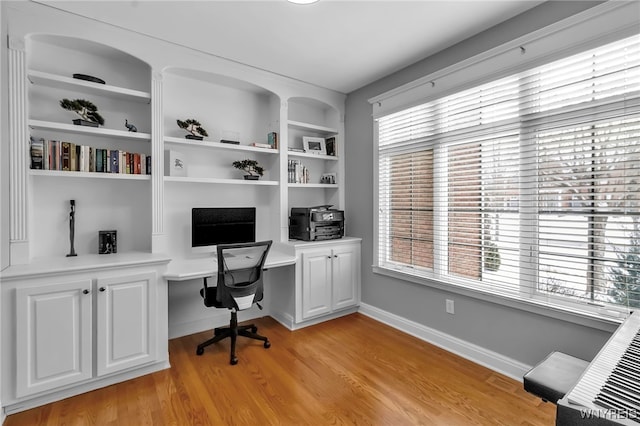 office featuring built in shelves, built in desk, and light hardwood / wood-style flooring