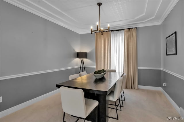 dining space featuring ornamental molding, light carpet, a chandelier, and a tray ceiling