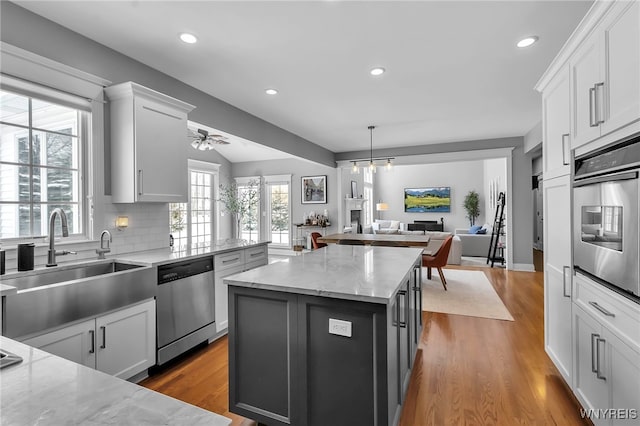 kitchen featuring sink, white cabinetry, a center island, stainless steel appliances, and light stone countertops