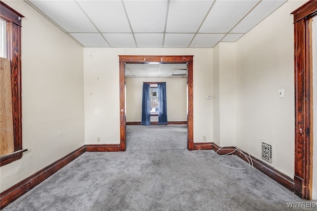 carpeted spare room featuring a drop ceiling