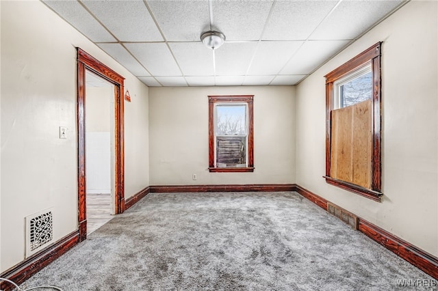 carpeted spare room with a drop ceiling