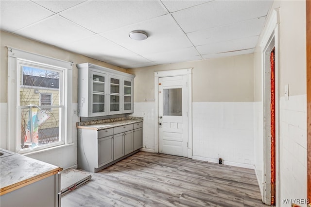 kitchen with gray cabinetry, a drop ceiling, a healthy amount of sunlight, and light wood-type flooring