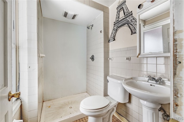 bathroom featuring toilet, tile walls, and a shower