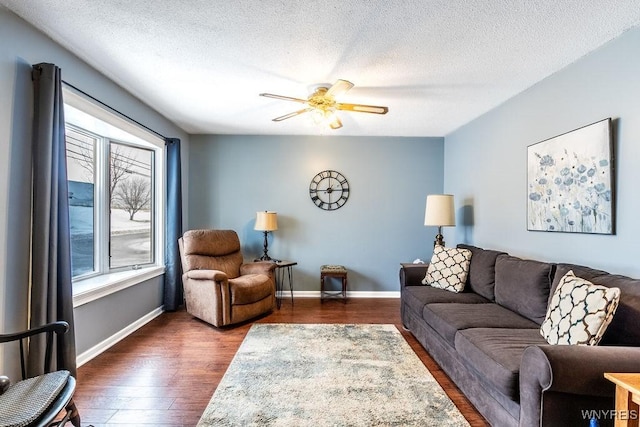 living room featuring ceiling fan, dark wood-type flooring, and a textured ceiling