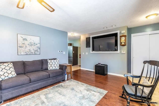 living room featuring a textured ceiling, wood-type flooring, and ceiling fan