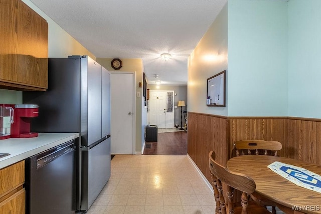 kitchen with a textured ceiling, wooden walls, and dishwasher