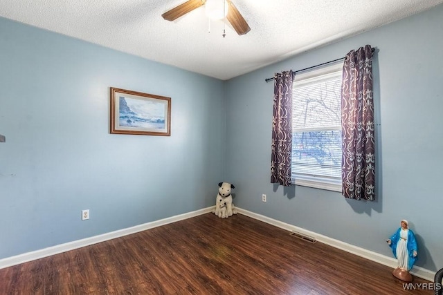 empty room with a textured ceiling, dark wood-type flooring, and ceiling fan