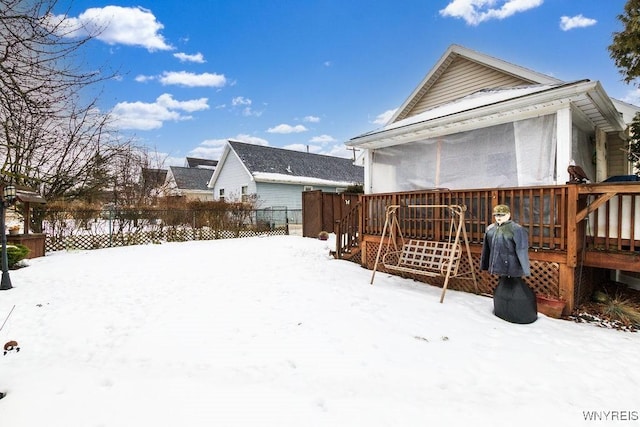 snow covered rear of property with a deck