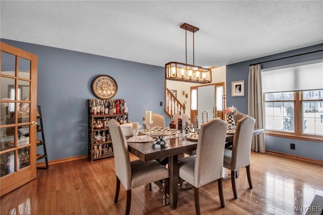 dining room with an inviting chandelier, light hardwood / wood-style flooring, and a textured ceiling