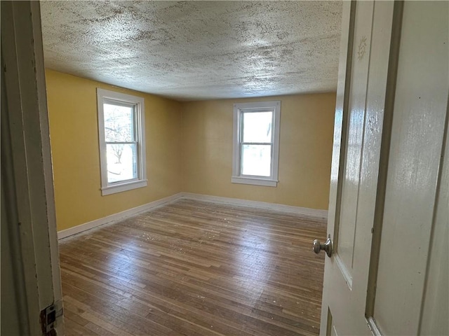 empty room with hardwood / wood-style floors and a textured ceiling