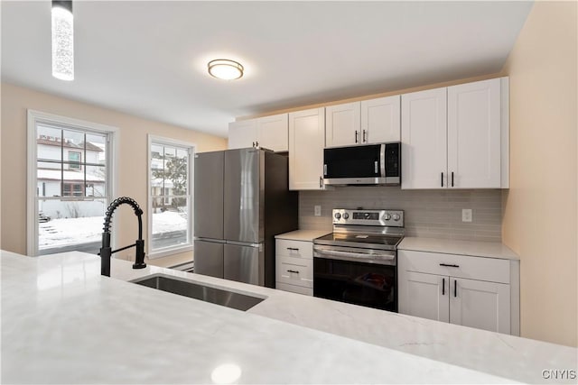 1208 James St, Syracuse, NY 13203 - kitchen with white cabinetry, appliances with stainless steel finishes, sink, and decorative backsplash