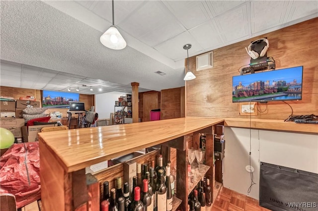 bar featuring parquet floors, a textured ceiling, butcher block countertops, and decorative light fixtures